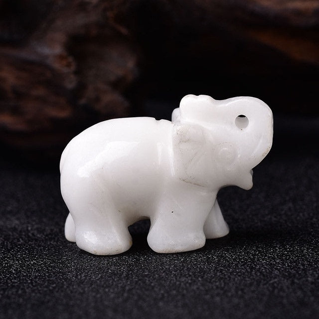 White healing crystal elephant stone carving from Sacred Moon Candle Co on black surface